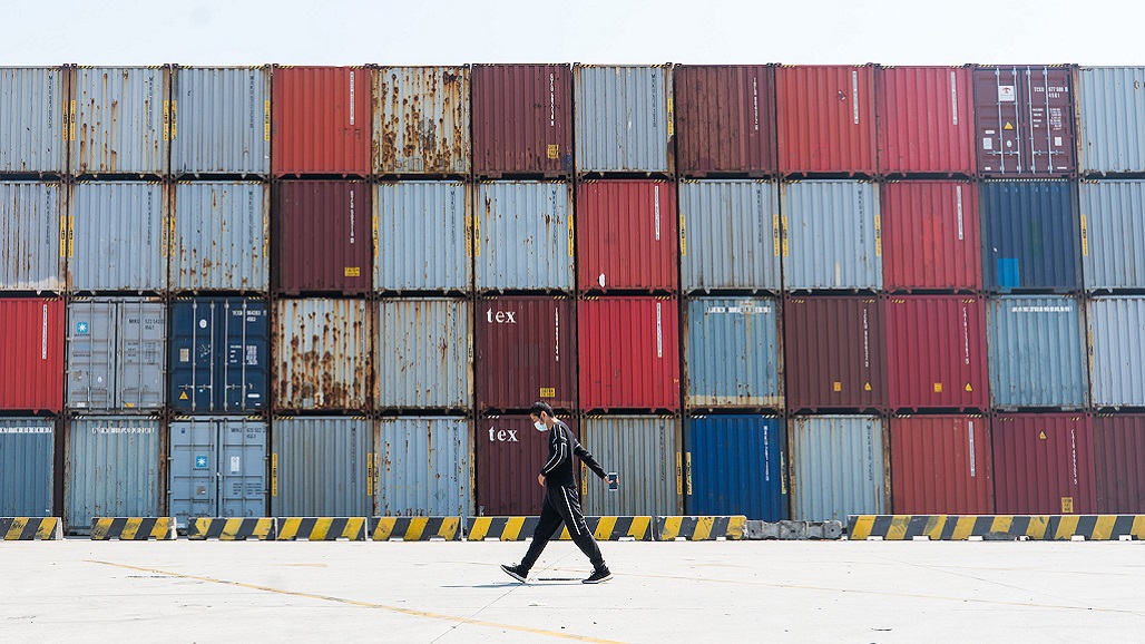 SHANGHAI, CHINA - MARCH 18: A truck driver wearing a protective mask walks past containers at Yangshan port on March 18, 2020 in Shanghai, China. Health authorities of China said the country has passed the peak of the COVID-19 epidemic on March 12. Since the outbreak began in December last year, the novel coronavirus (COVID-19) has infected more than 203,000 people and killed over 8,200 globally. The World Health Organization (WHO) declared the rapidly spreading coronavirus outbreak a pandemic on March 11. (Photo by Yves Dean/Getty Images)